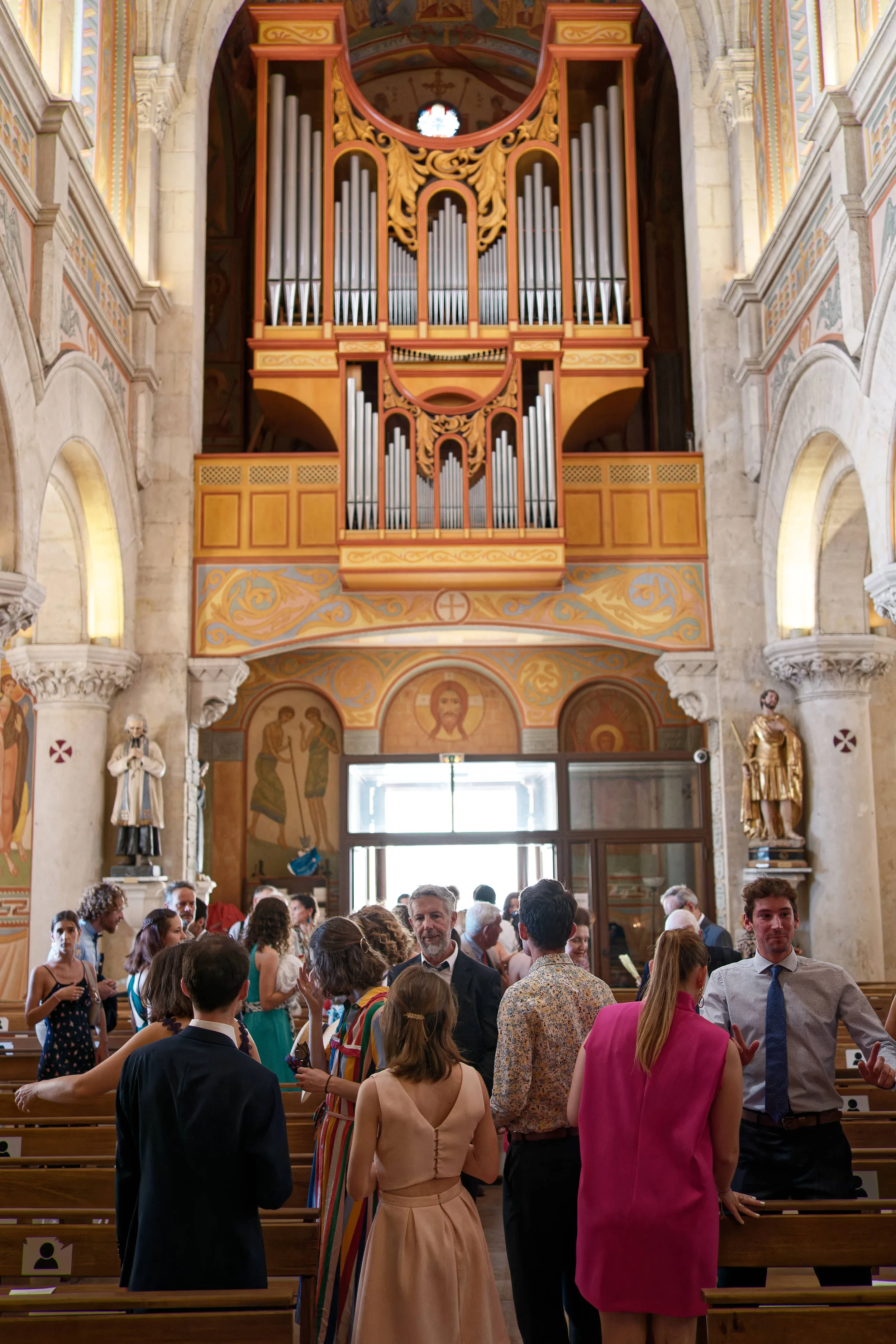 L’orgue aux tons dorés domine la nef, où les invités se retrouvent entre les bancs sous les arches peintes.