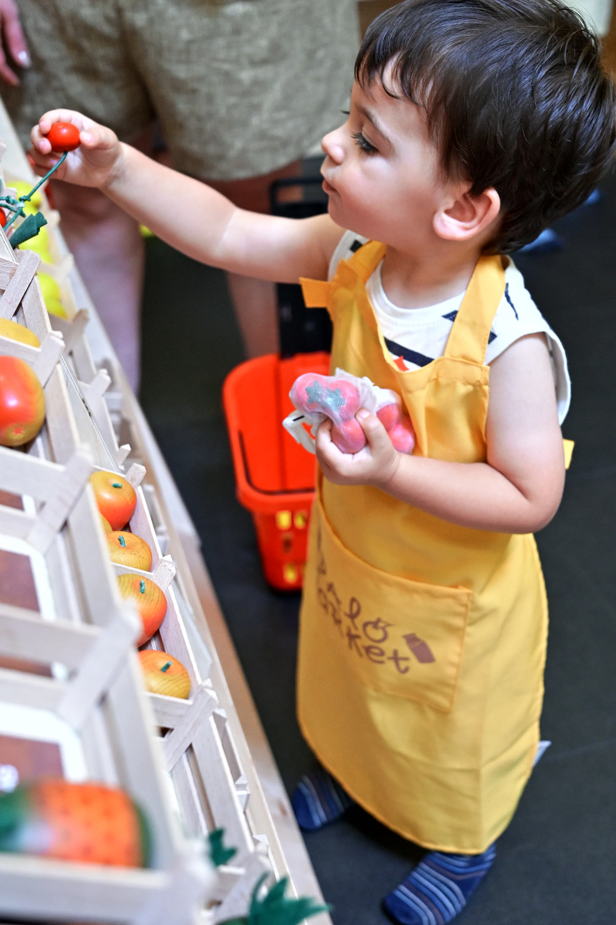 Enfant en tablier choisissant un fruit dans le supermarché de Palomano Toulon