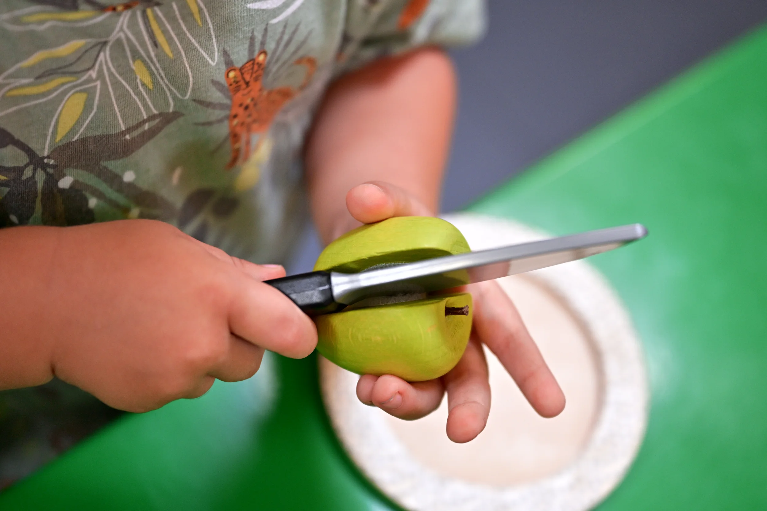Mains d’un enfant découpant une pomme en bois à Palomano Toulon