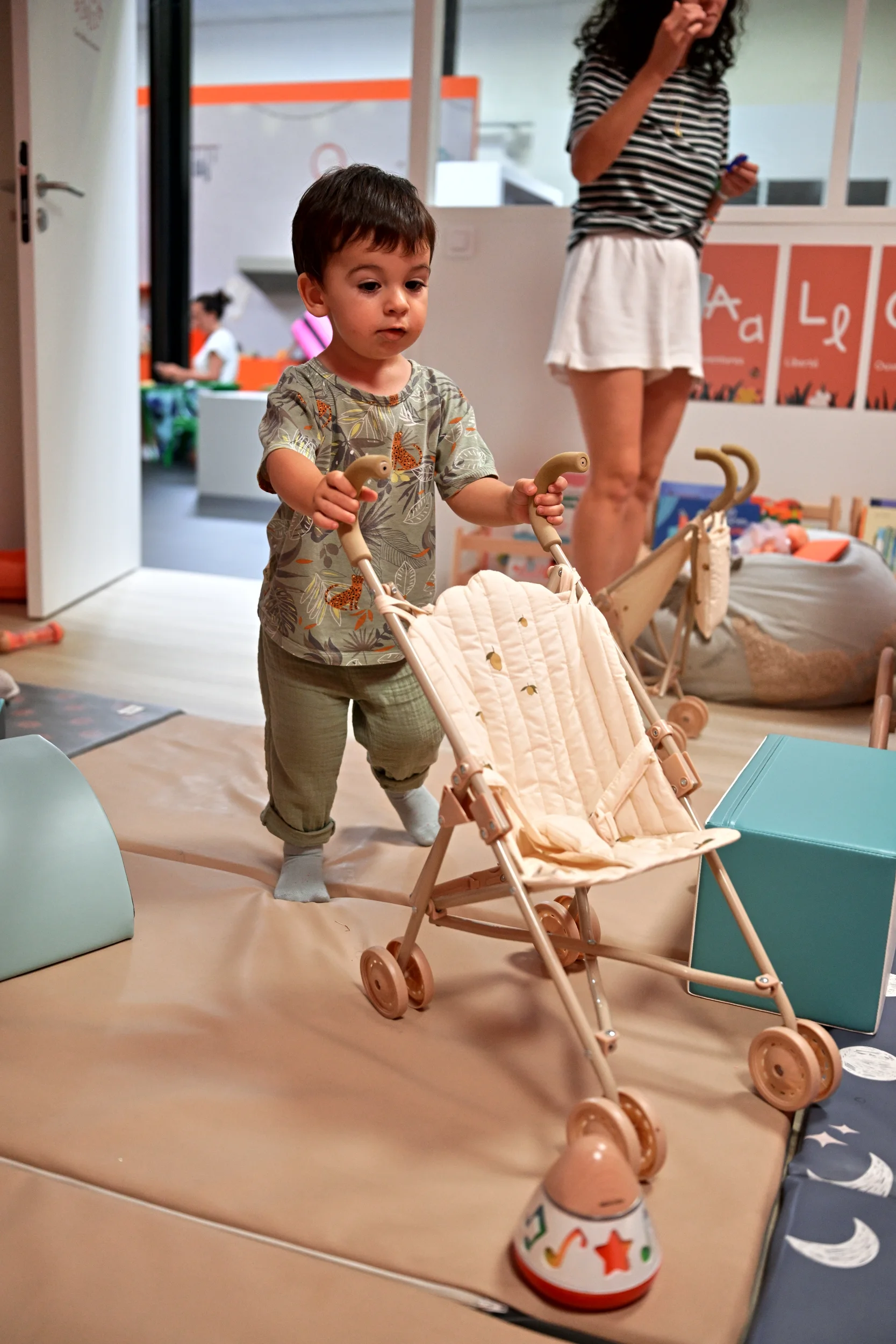 Enfant jouant avec une poussette dans l’espace des tout-petits de Palomano Toulon