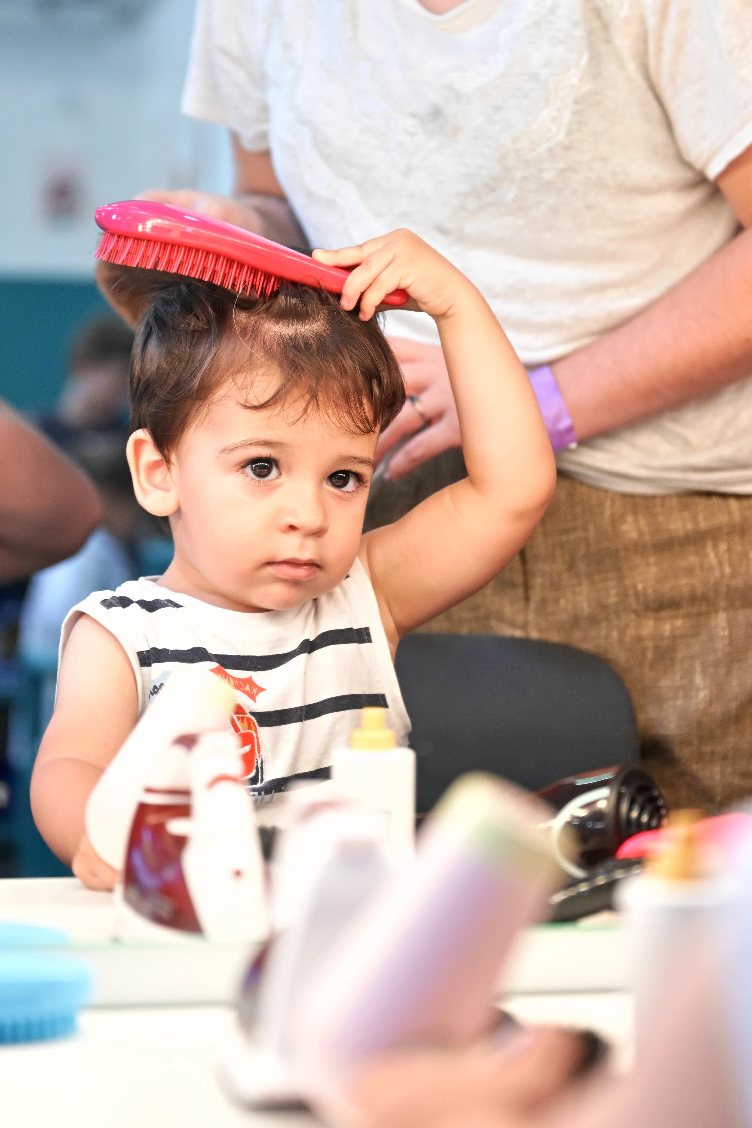 Enfant se coiffant avec une grande brosse dans le salon de coiffure de Palomano Toulon