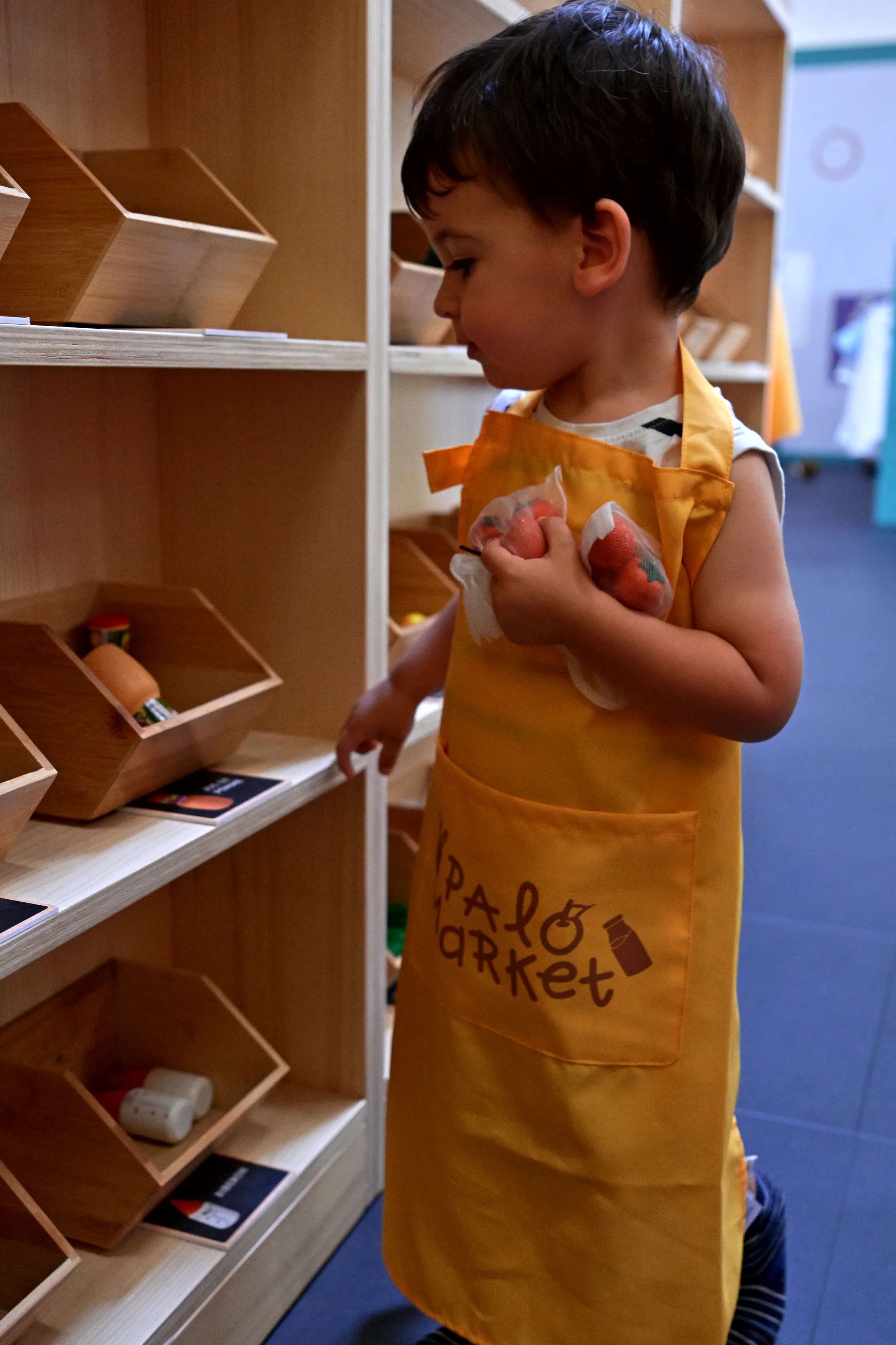 Enfant en tablier observant les rayons en bois du supermarché Palomano Toulon