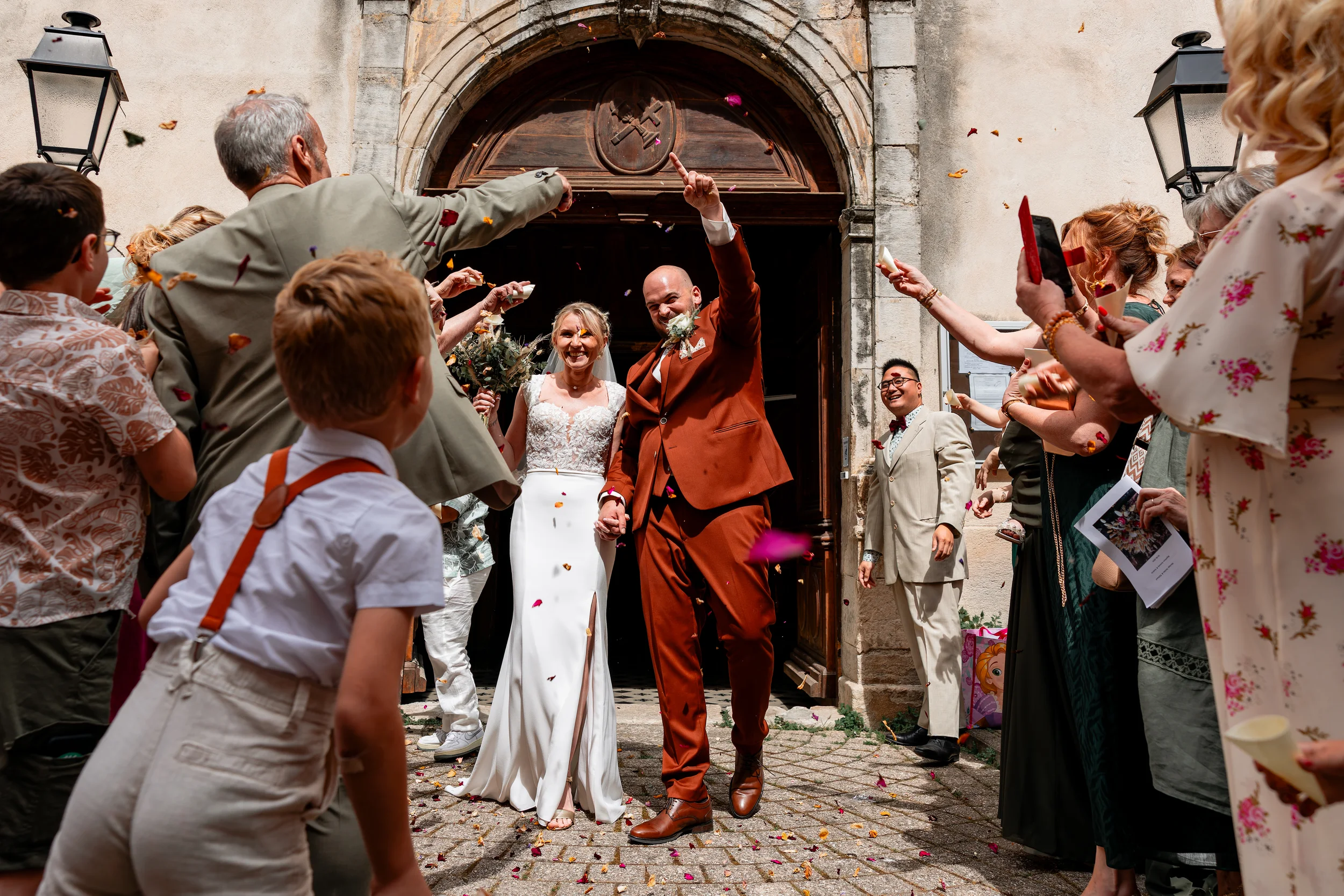 Sortie d'église des mariés entourés de leurs invités et de confettis